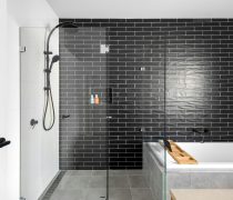 Sleek and modern bathroom featuring a black tiled wall and glass shower enclosure.